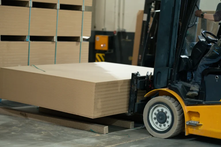 Forklift moving stacks of carton board in a warehouse, highlighting HS Agency's logistics capabilities for transporting essential raw materials. Efficient warehousing and transportation solutions tailored for the paper and construction industries.