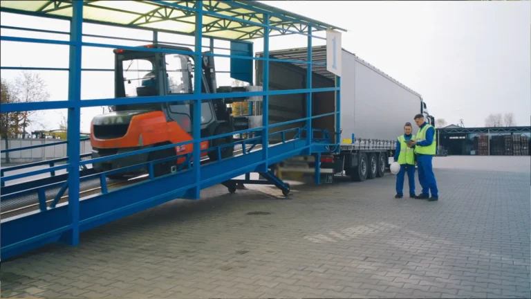 Workers at HS Agency oversee the loading process of a forklift onto a truck at a logistics facility, showcasing the company's commitment to efficient transportation and comprehensive logistical solutions across the U.K. and Ireland.