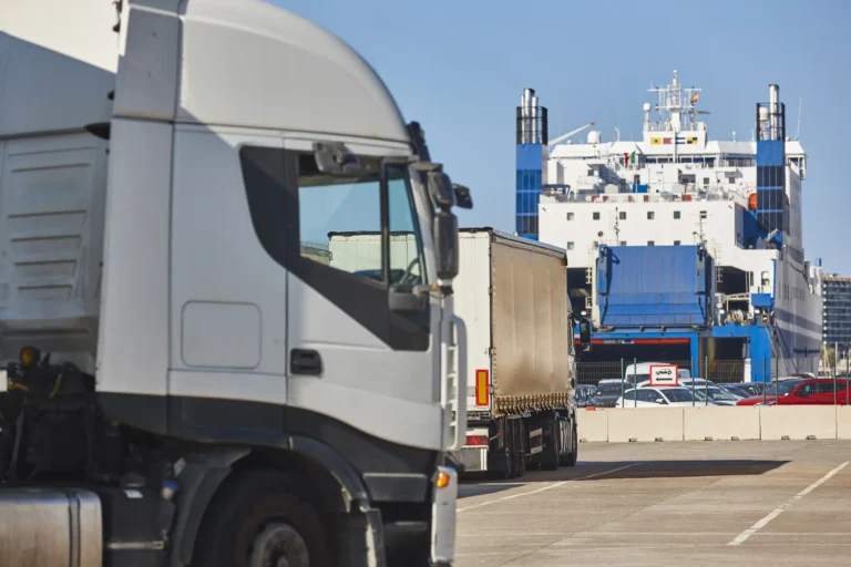 Trucks lined up at a port with a cargo ship in the background, representing HS Agency's logistics solutions for efficient transportation and warehousing services across the UK and Ireland.